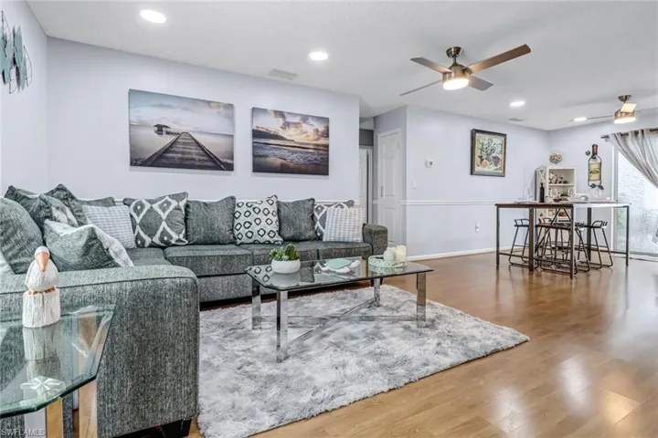 Living area featuring wood finished floors, a ceiling fan, baseboards, and recessed lighting
