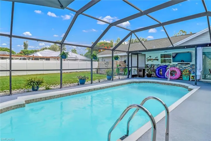 View of swimming pool featuring fence, glass enclosure, and a patio area