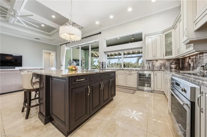 Open kitchen featuring white cabinetry, granitecountertops, and wine cooler