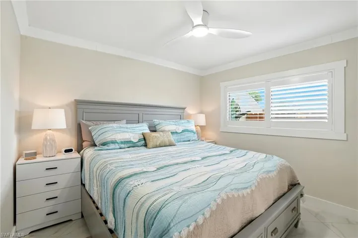 Bedroom featuring crown molding, a ceiling fan, and light marble finish floors