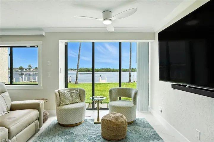 Living area featuring ceiling fan, tile patterned floors, and a textured wall