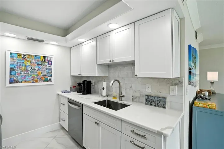 Kitchen featuring white cabinetry, backsplash, stainless steel dishwasher, and recessed lighting
