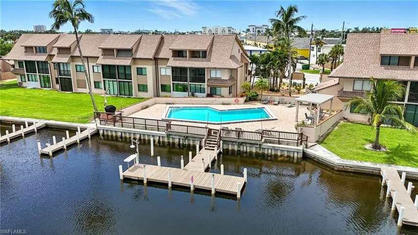 Dock featuring a patio, a water view, a community pool, and a lawn