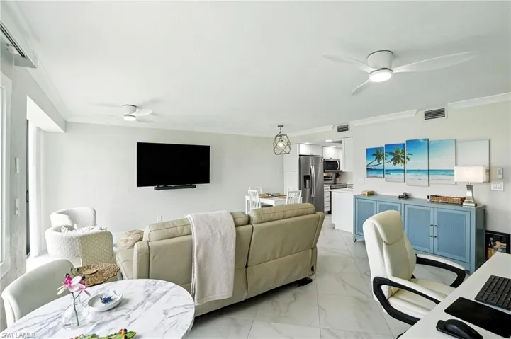 Living room featuring ceiling fan, crown molding, light marble finish floors, and an office area