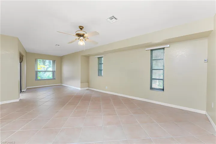 Spare room featuring light tile patterned floors, a ceiling fan, visible vents, and baseboards