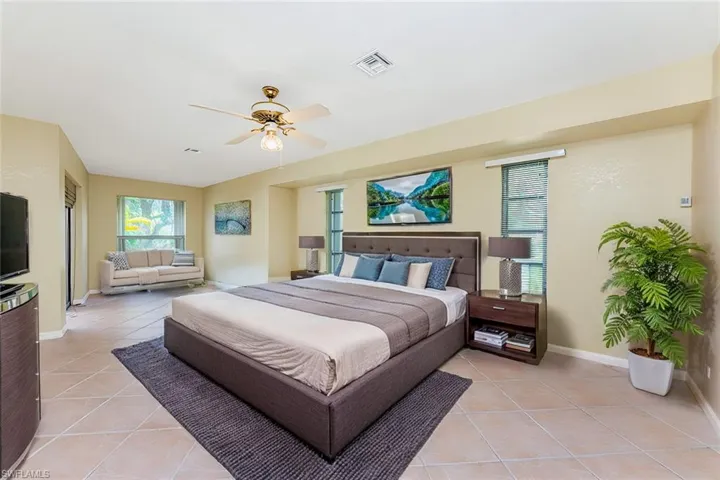 Virtual Staged Bedroom with light tile patterned floors, visible vents, a ceiling fan, and baseboards