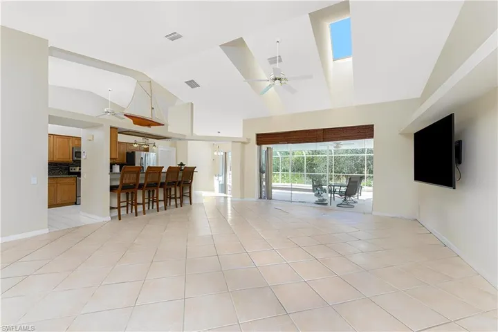 Living room with light tile patterned floors, baseboards, visible vents, and ceiling fan