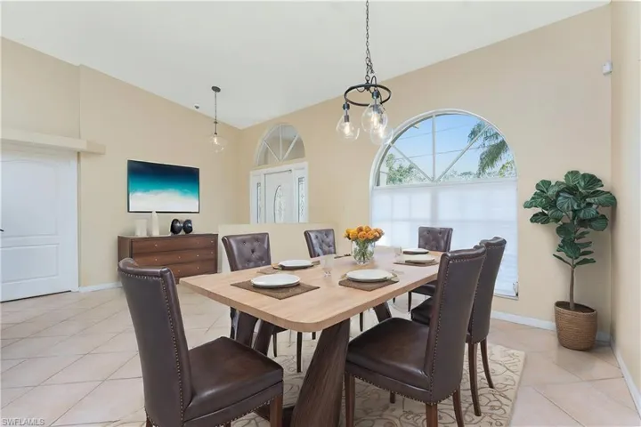 Virtual Staged Dining room featuring light tile patterned flooring, baseboards, and vaulted ceiling