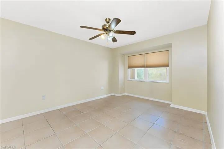 Spare room with light tile patterned floors, baseboards, and a ceiling fan