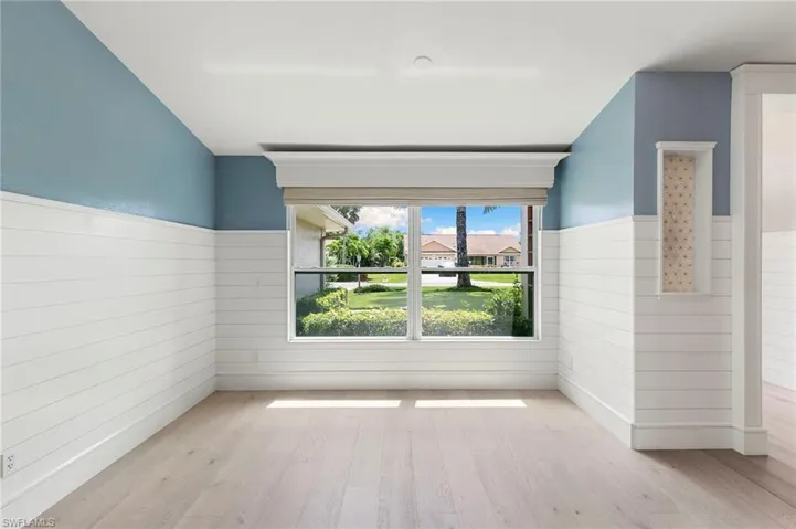 Spare room with wood finished floors and wainscoting