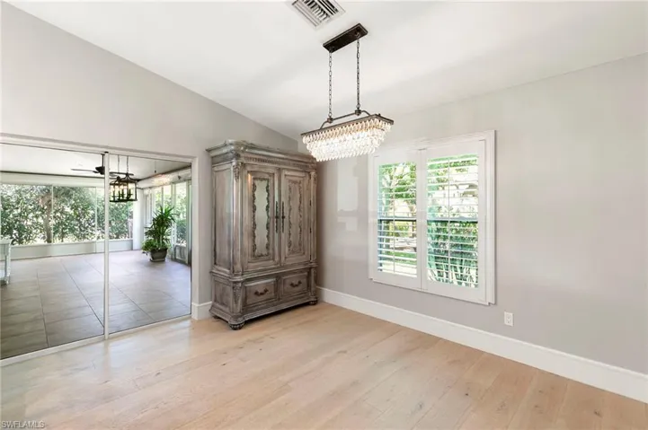 Unfurnished dining area with vaulted ceiling, light wood-style flooring, a chandelier, and a ceiling fan