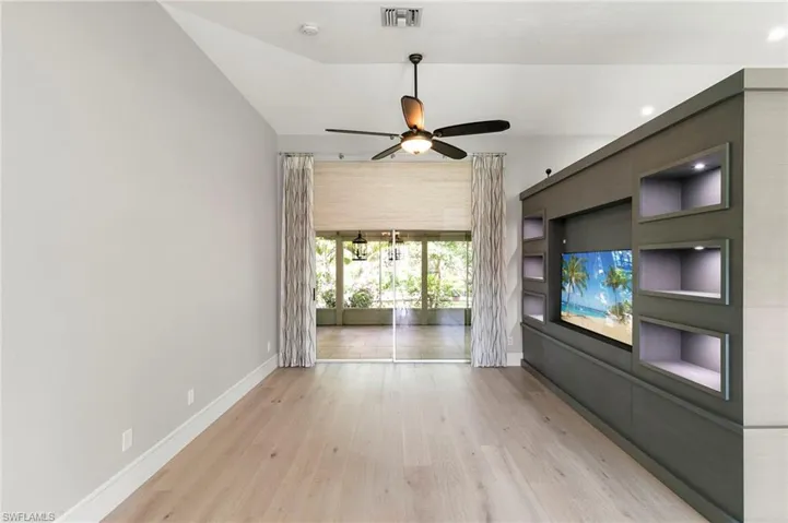 Unfurnished living room featuring wood finished floors, ceiling fan, and built in features