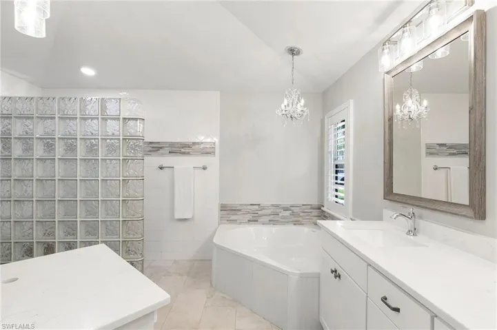 Bathroom featuring vanity, a garden tub, walk in shower, tile patterned floors, and tile walls