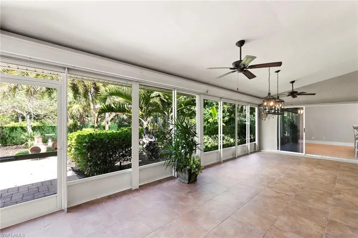 Unfurnished sunroom with lofted ceiling, a chandelier, and tile patterned flooring