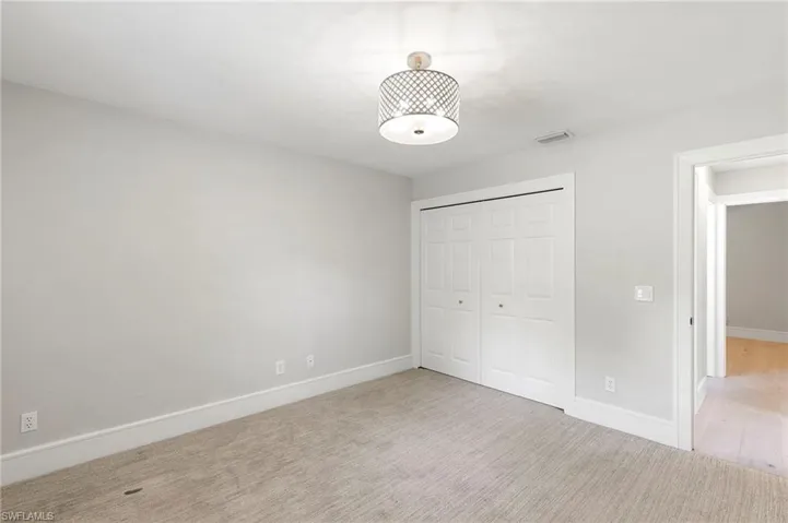 Unfurnished bedroom with light carpet and a closet