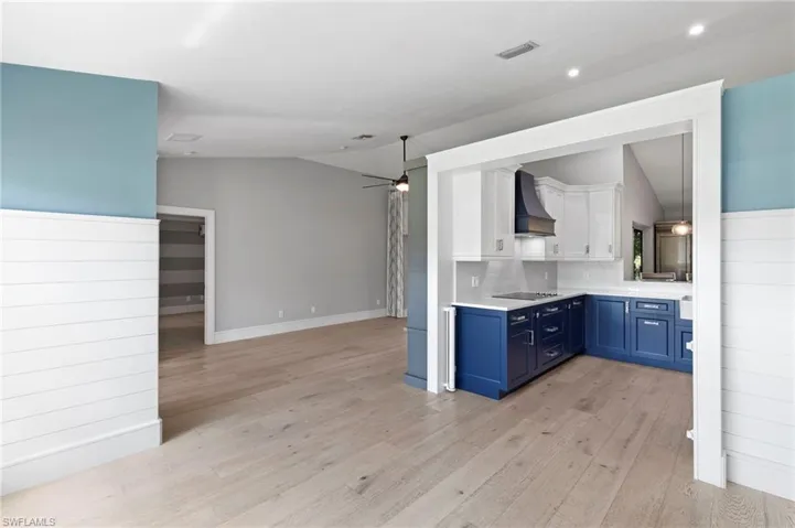 Kitchen with vaulted ceiling, blue cabinets, a ceiling fan, open floor plan, and light countertops