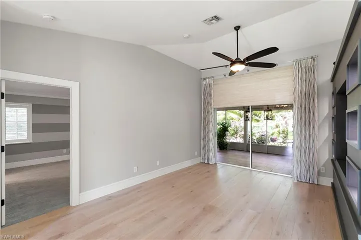 Spare room featuring plenty of natural light, light wood finished floors, lofted ceiling, and ceiling fan