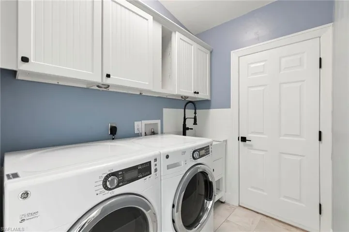 Washroom featuring washing machine and dryer, cabinet space, and light tile patterned flooring