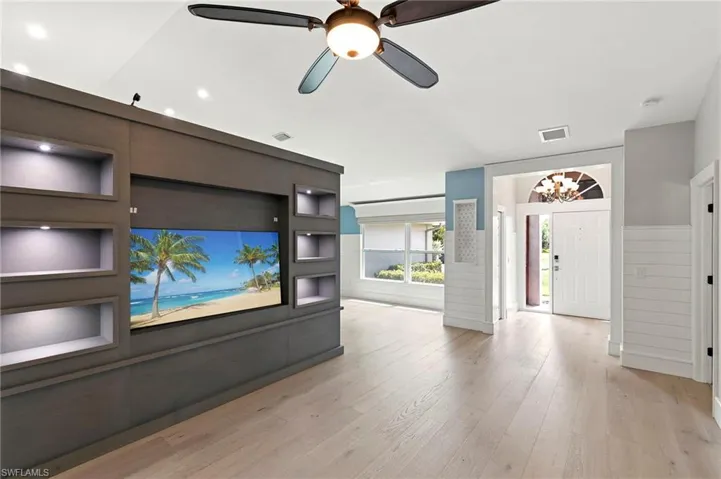 Unfurnished living room featuring a chandelier, light wood-style flooring, and a ceiling fan