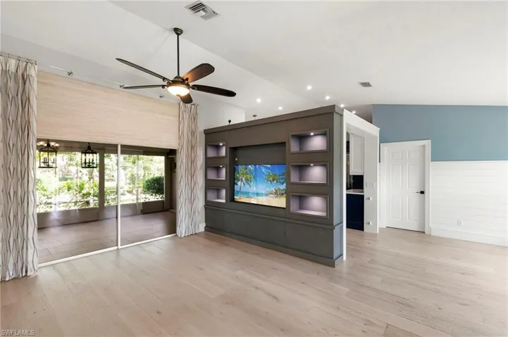 Unfurnished living room with wood finished floors, ceiling fan, recessed lighting, and lofted ceiling