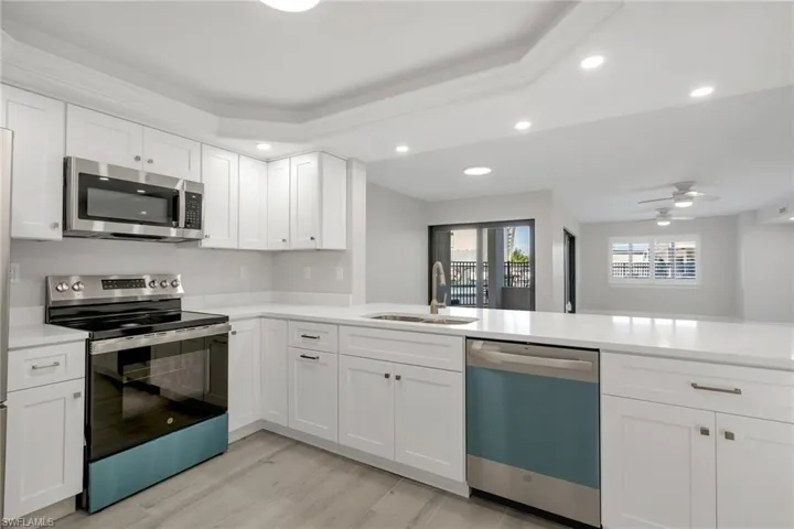 Kitchen featuring appliances with stainless steel finishes, white cabinetry, sink, kitchen peninsula