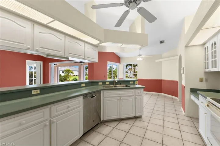 Kitchen featuring light tile patterned floors, dishwasher, ceiling fan, sink, and white cabinetry