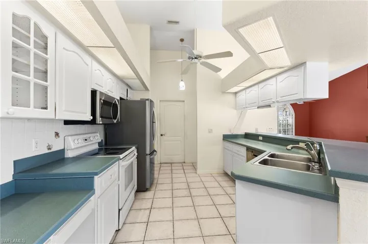 Kitchen featuring ceiling fan, appliances with stainless steel finishes, light tile patterned floors, backsplash, and sink