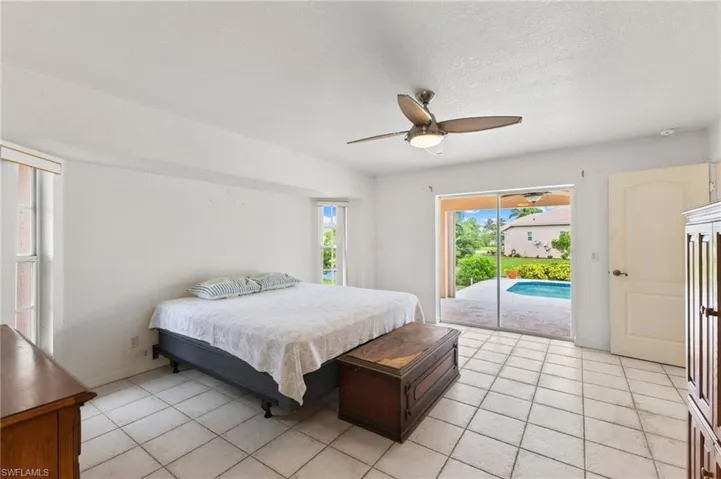 Bedroom with ceiling fan, light tile patterned flooring, and access to outside