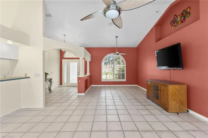 Unfurnished living room featuring high vaulted ceiling, light tile patterned floors, and ceiling fan
