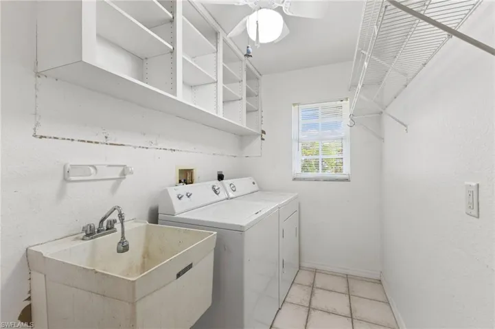 Washroom with ceiling fan, sink, washing machine and clothes dryer, and light tile patterned floors
