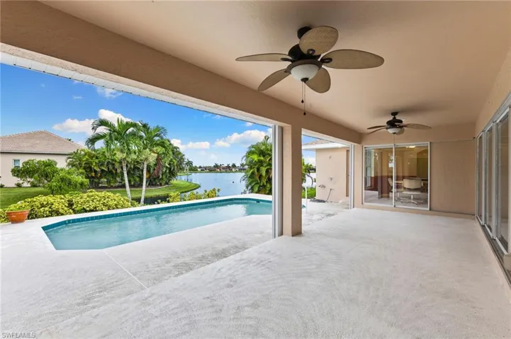 View of pool with ceiling fan, a patio, and a water view