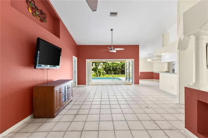 Unfurnished living room featuring ceiling fan, light tile patterned flooring, high vaulted ceiling, and ornate columns