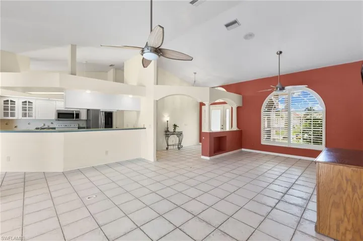 Unfurnished living room with ceiling fan, high vaulted ceiling, and light tile patterned floors