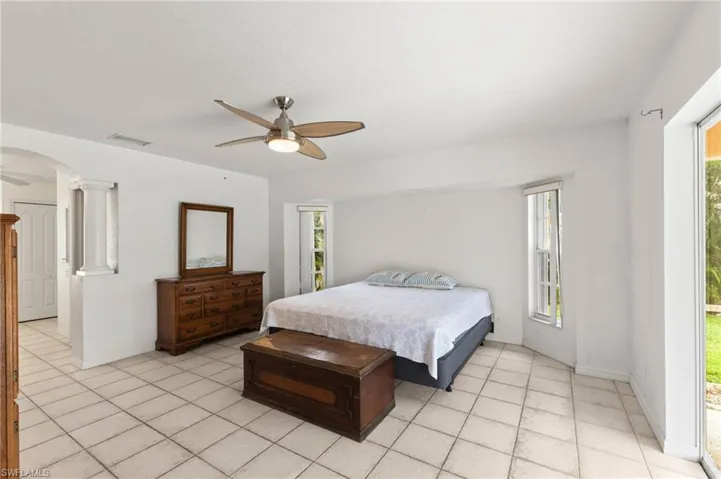 Primart Bedroom with ceiling fan, decorative columns, and light tile patterned floors