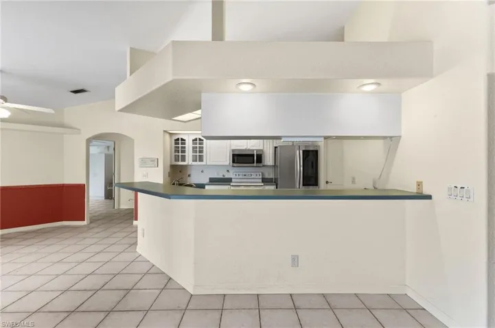 Kitchen with light tile patterned floors, appliances with stainless steel finishes, ceiling fan, white cabinetry, and kitchen peninsula