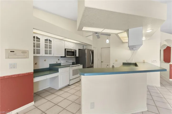 Kitchen with ceiling fan, light tile patterned flooring, stainless steel appliances, and kitchen peninsula