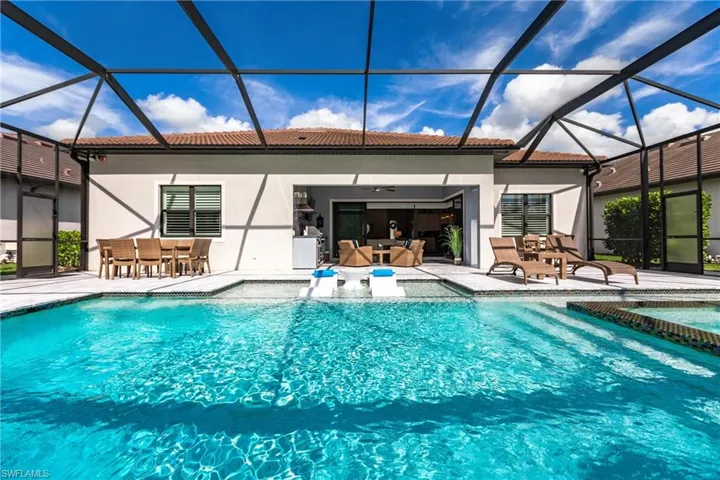 View of pool with glass enclosure, a patio, and an outdoor hangout area