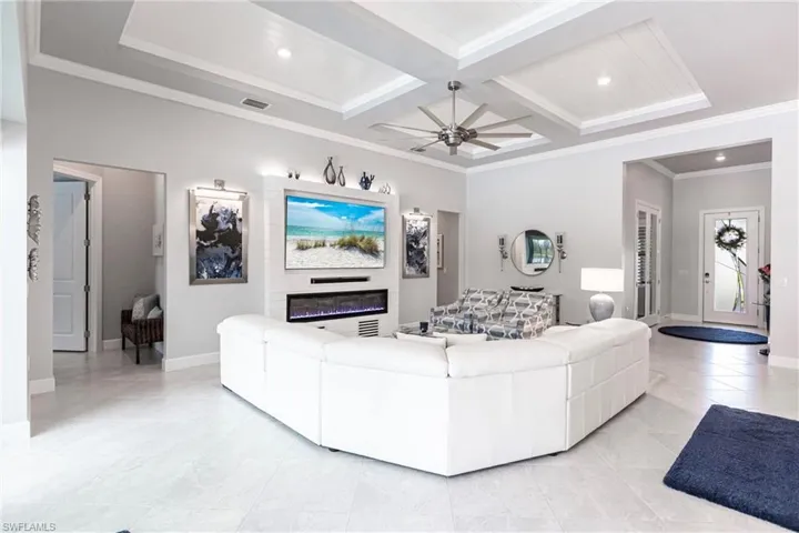 Tiled living room featuring beamed ceiling, ornamental molding, ceiling fan, and coffered ceiling