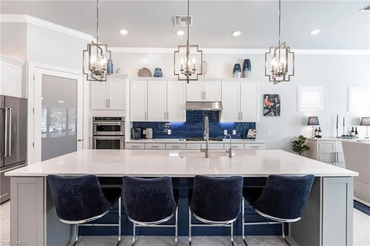 Kitchen featuring pendant lighting, a large island, and light stone counters