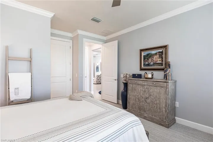 Carpeted bedroom with ceiling fan and ornamental molding