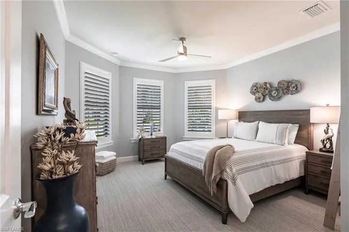 Bedroom with light colored carpet, ceiling fan, and crown molding