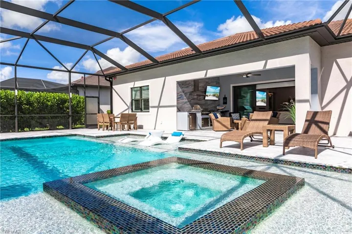 View of swimming pool featuring an in ground hot tub, an outdoor kitchen, glass enclosure, and a patio area