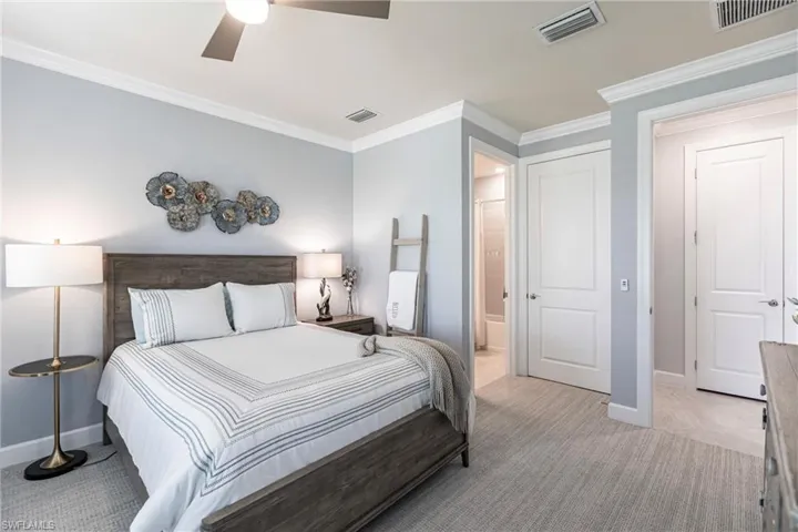 Bedroom featuring light carpet, ceiling fan, crown molding, connected bathroom, and a closet