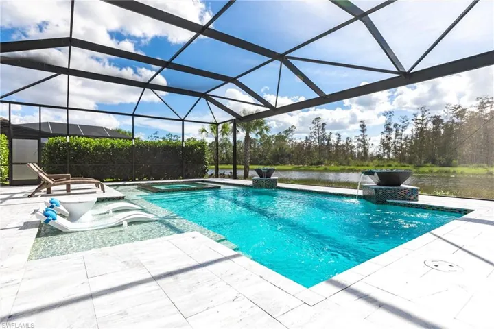 View of swimming pool with a lanai, pool water feature, an in ground hot tub, a water view, and a patio