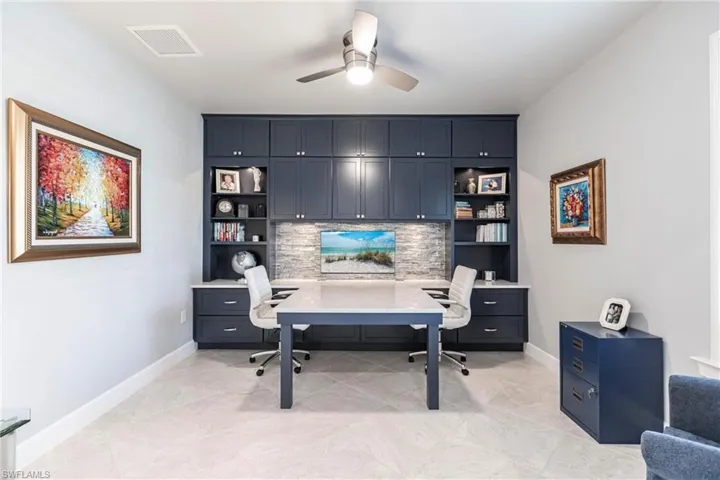 Office with built in shelves, ceiling fan, and built in desk