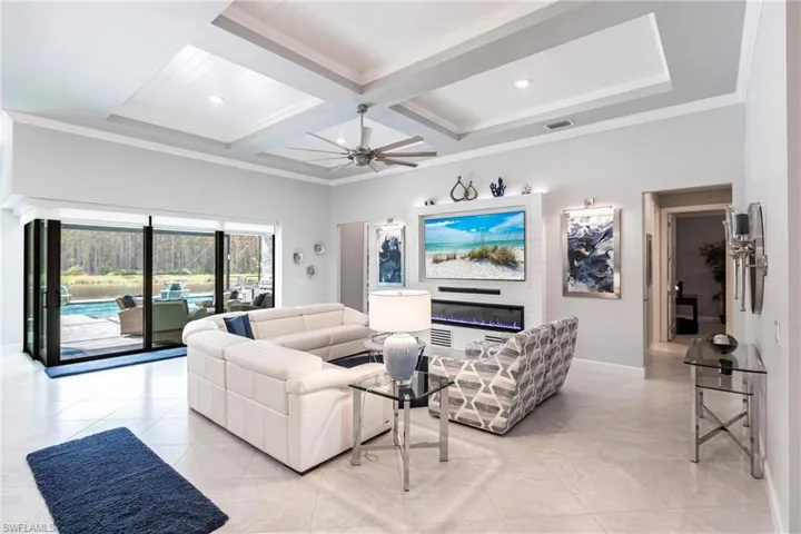 Tiled living room with beamed ceiling, crown molding, ceiling fan, and coffered ceiling