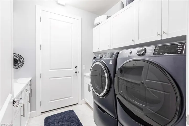 Washroom featuring washing machine and clothes dryer and cabinets