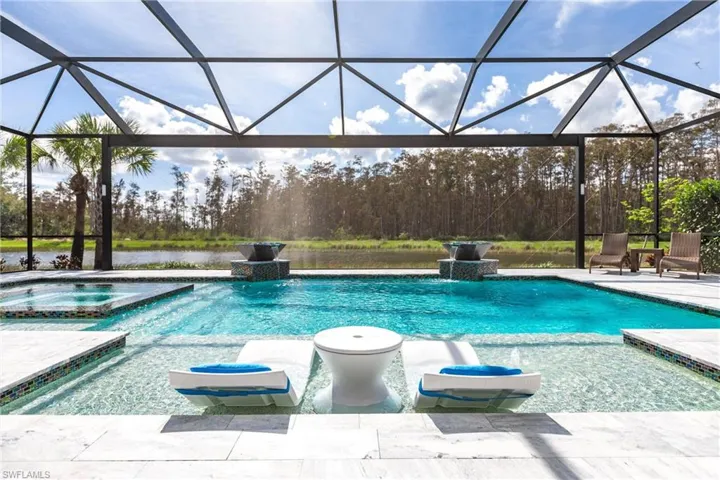 View of pool featuring a water view, pool water feature, a lanai, an in ground hot tub, and a patio area
