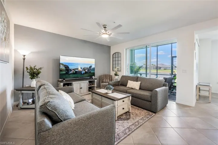 Living area featuring light tile patterned flooring, baseboards, and ceiling fan