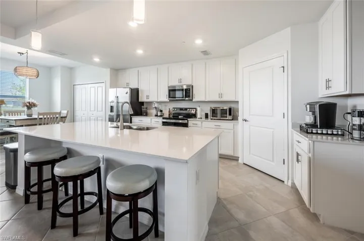 Kitchen with visible vents, a kitchen bar, an island with sink, a sink, and appliances with stainless steel finishes